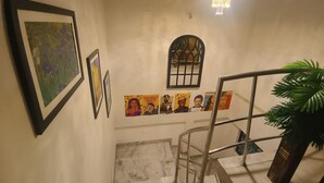 A staircase with a metal railing, a potted plant, and a series of framed artworks on the walls. - Daisy Duplex (Nagpur)