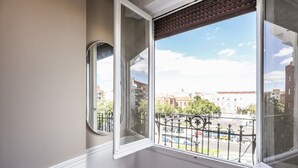 Una habitación en esquina con un ventanal grande, un espejo y suelo de madera.