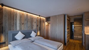 Un dormitorio moderno con cabecera de madera, cama con ropa de cama a cuadros y vestidor con puertas de madera.