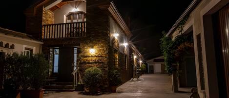 A two-story building with a balcony, stone facade, and potted plants.