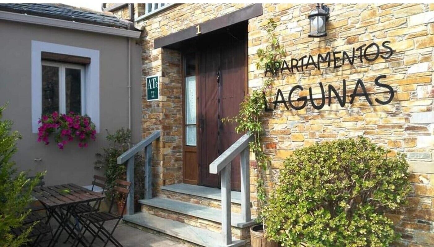 Ein Gebäude mit einer Steinauffachung, einer Holztür und einem Schild mit der Aufschrift 'APARTAMENTOS LAGUNAS'.