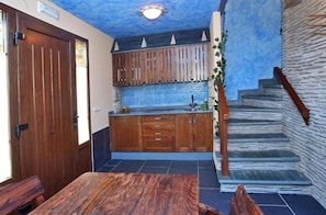 A kitchen with wooden cabinets, a blue tiled backsplash, and a wooden staircase.
