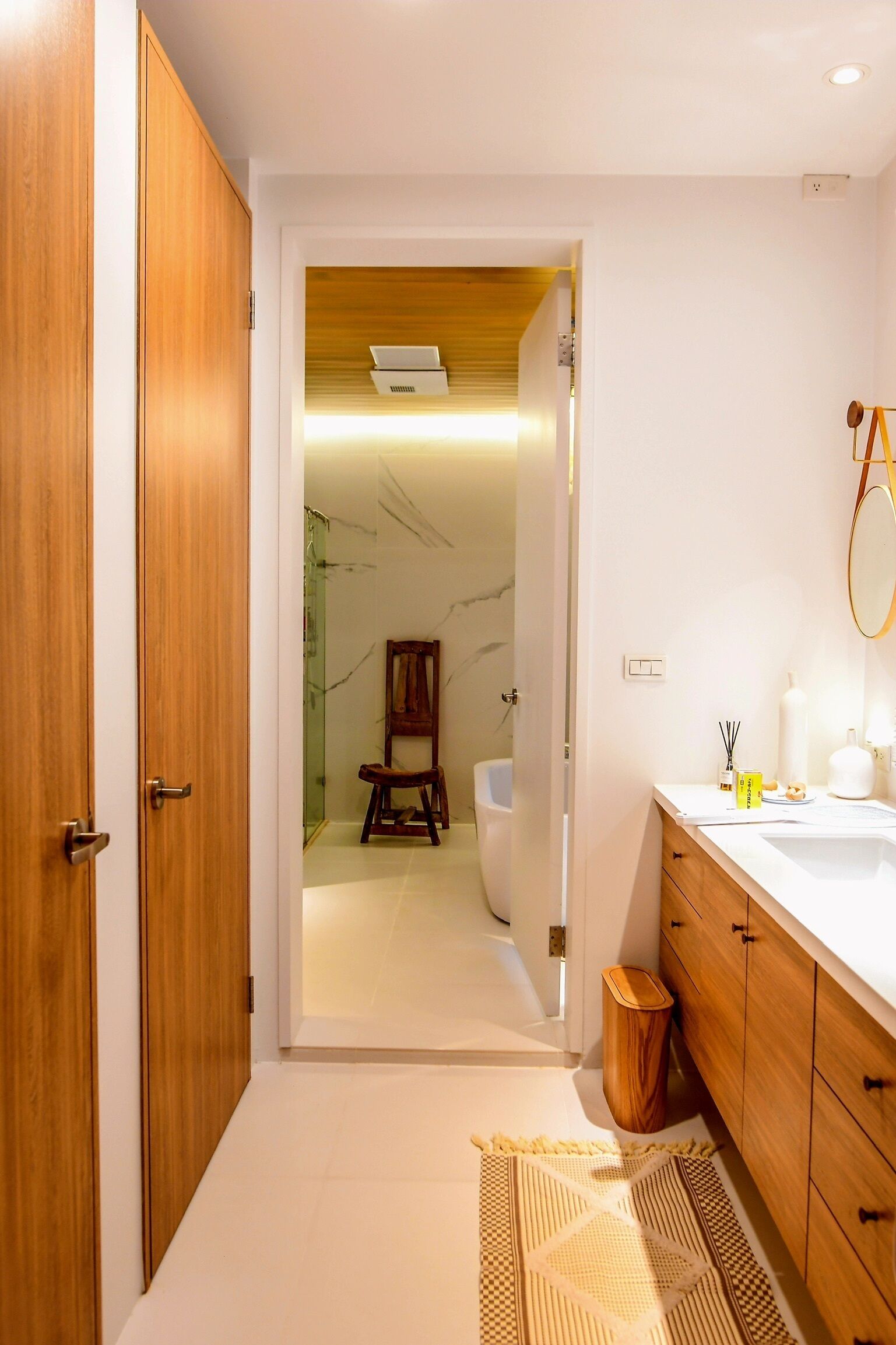Un baño moderno con armarios de madera, un lavabo blanco y un espejo.