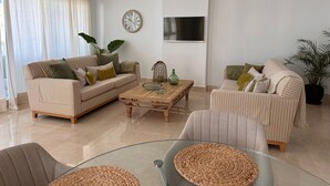 A modern living room with striped sofas, a coffee table, and a glass table with woven placemats.