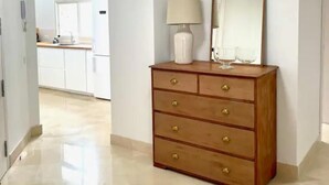 A hallway with a wooden dresser, a mirror, and a lamp.