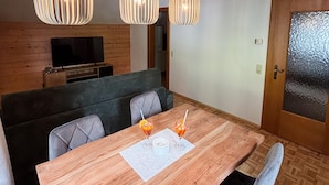A wooden dining table with two glasses of orange juice and a white napkin.