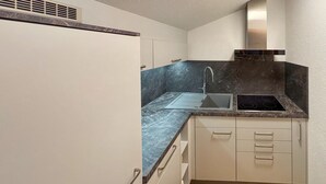 A compact kitchen with a built-in stove, a sink, and white cabinetry.