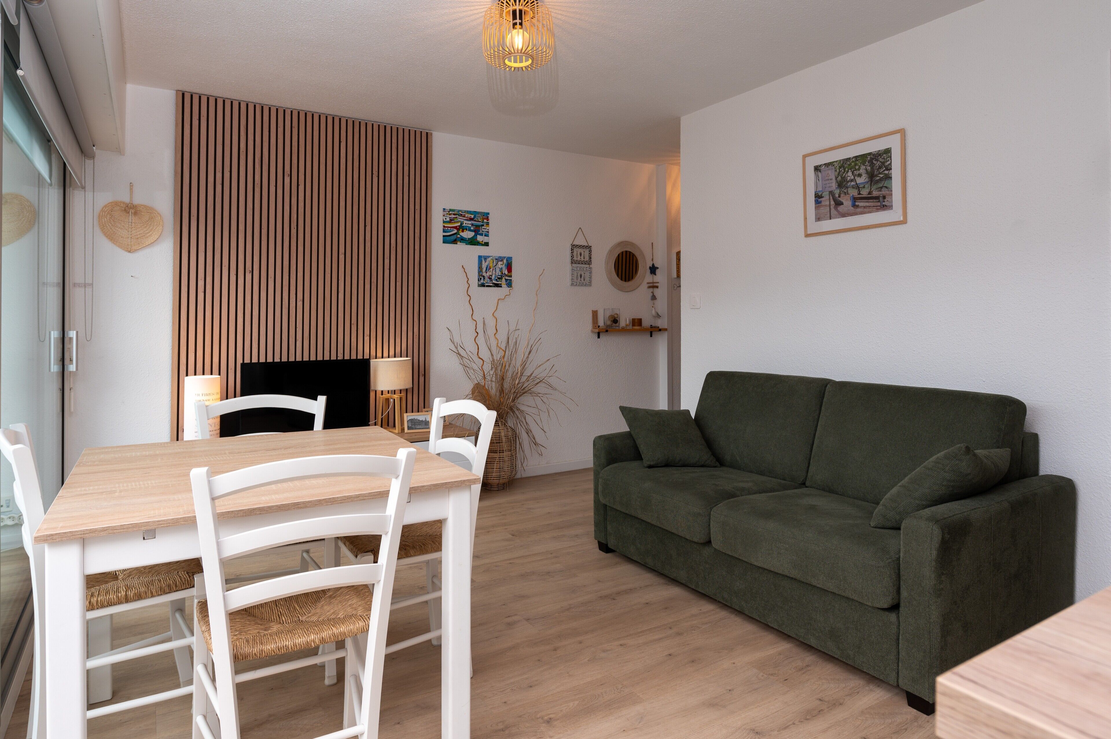 Una sala de estar con una mesa de comedor de madera, sillas blancas, un sofá verde y una chimenea.