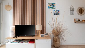 Ein modernes Wohnzimmer mit Fernseher, Lampe und dekorativen Gegenständen auf einer Holzkonsolen.