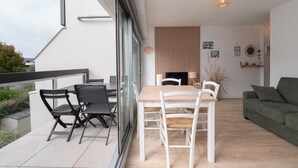 Ein modernes Wohnzimmer mit Essbereich, einem grünen Sofa und einem Kamin.