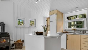 A modern kitchen with a central island, white cabinetry, and a built-in stove. - "Martina" - 500m from the sea by Interhome (Jerup)