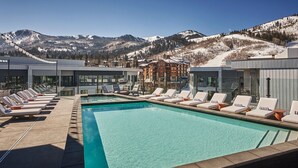 A pool area with lounge chairs and a view of mountains.