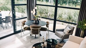 A modern living room with a large window, a round dining table, and comfortable seating.