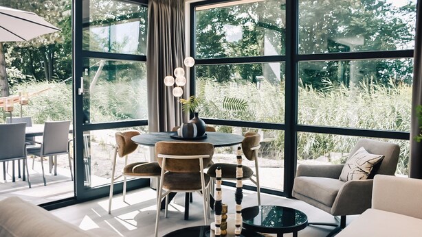 A modern living room with a large window, a round dining table, and a sofa.