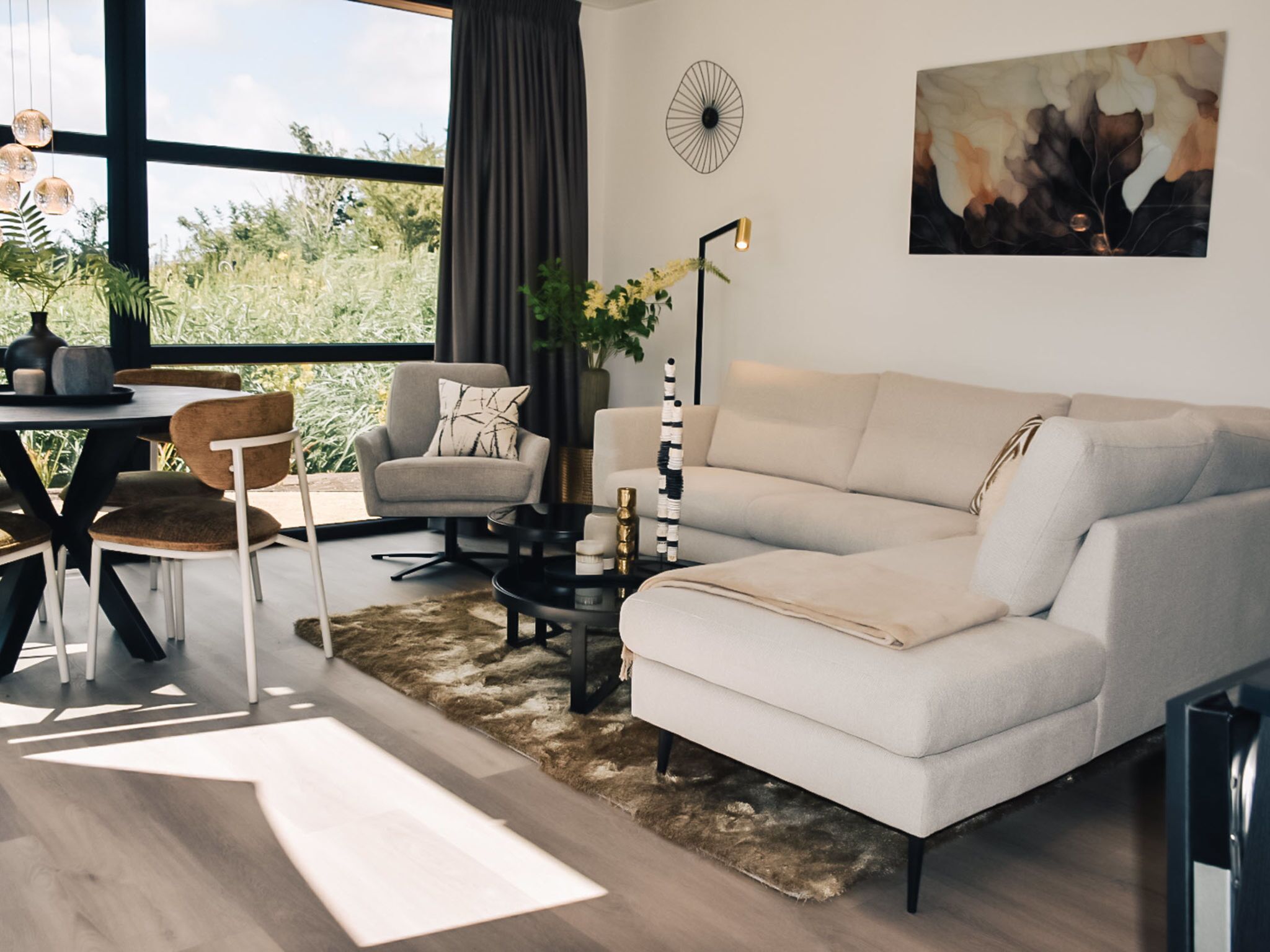 Un salon moderne comprenant un canapé, des fauteuils, une table basse et un coin repas avec des chaises et une table.