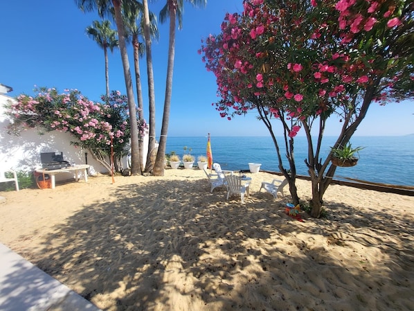 A beachside patio with a laptop, chairs, and potted plants. - Villa 'Beachfront' with Sea View, Wi-Fi and Air Conditioning (ESTEPONA)