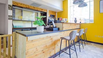 Una cocina moderna con detalles de madera, una zona de bar con taburetes y un amplio ventanal que proporciona luz natural.