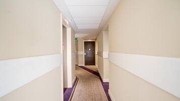 A hotel hallway with a carpeted floor, doors on both sides, and a ceiling with recessed lighting.