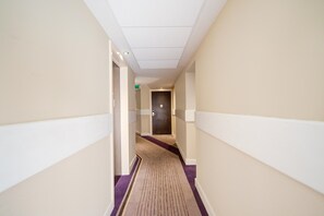 A hotel hallway with a carpeted floor, doors on both sides, and a ceiling with recessed lighting. - Belvilla Newport City Centre Hotel - Deluxe Double Room (Newport)