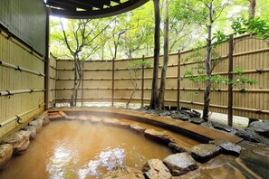 A traditional Japanese onsen with a natural pool, bamboo walls, and a forested backdrop. - Raconter Arima (Kobe)