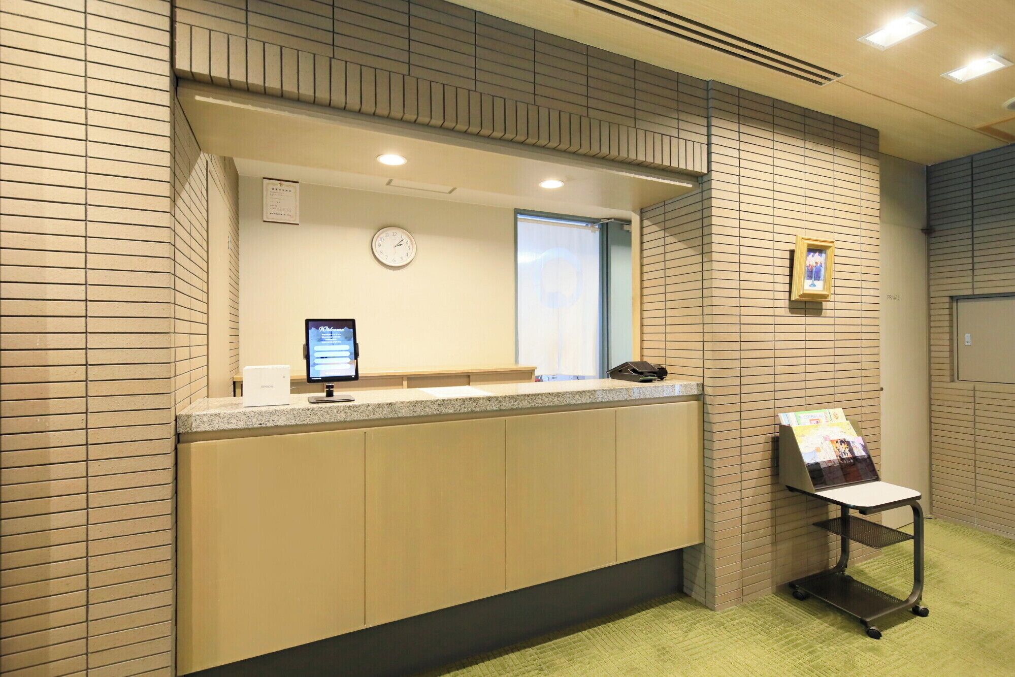 A reception desk with a computer monitor, a clock, and a framed picture on the wall.