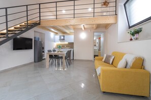 Un intérieur moderne comprenant un escalier, un coin repas, une cuisine et un salon avec un canapé.