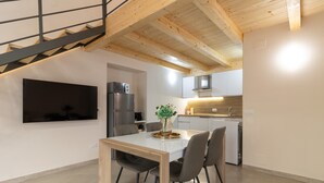 Una cocina moderna con comedor, vigas de madera en el techo y un televisor de pantalla plana montado en la pared.