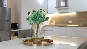 Una cocina moderna con una mesa de comedor, un florero con flores y un refrigerador.