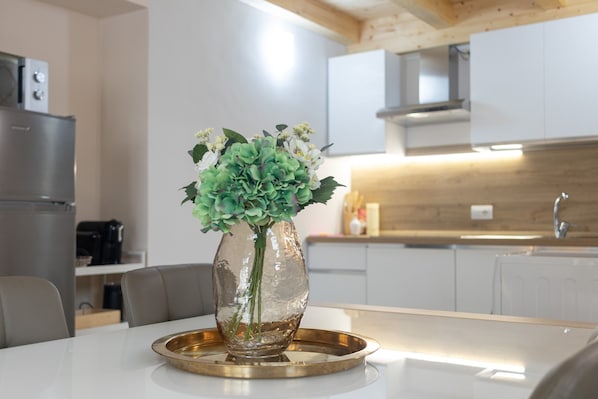 Une cuisine moderne avec une table à manger, un vase de fleurs et un réfrigérateur.