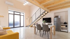 Un espacio habitable moderno con una escalera, comedor, sofá y cocina.