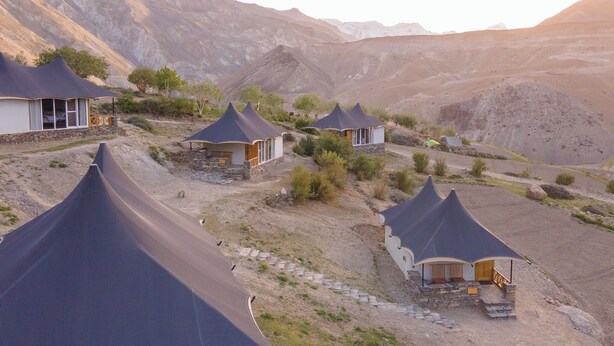 A series of dome-shaped tents with stone foundations, set against a mountainous backdrop. - Tara Mountain Sarai (Kargil)