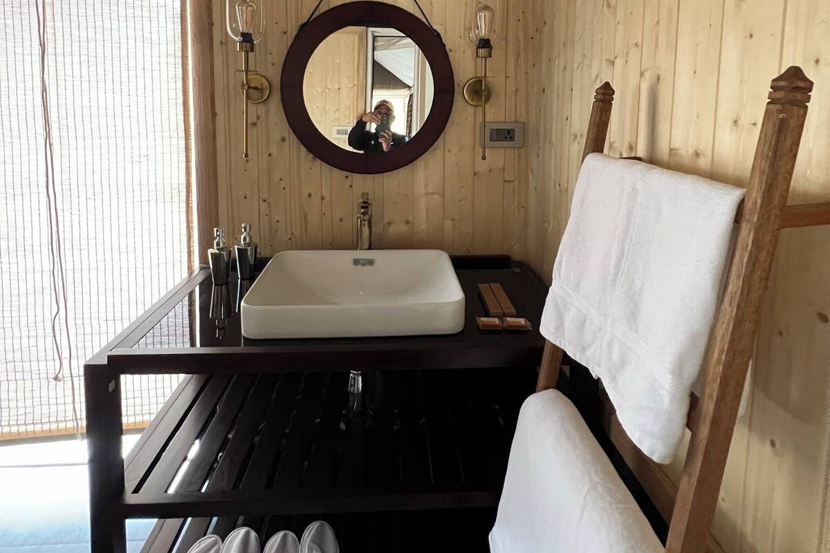 Une salle de bain rustique, avec des murs en bois, un grand miroir, un lavabo et un porte-serviettes.