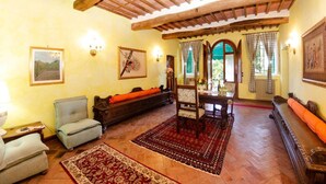 Un salón acogedor con techo de madera, alfombra estampada y un sofá con cojín naranja.