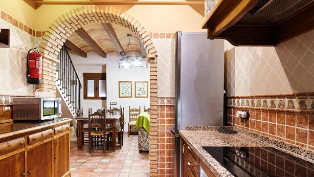 A kitchen with a tiled floor, wooden cabinets, a refrigerator, and a stove. - Rural House 'La Acacia' with Private Pool, Wi-Fi and Air Conditioning (Martos)
