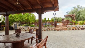 An outdoor patio with a wooden table and chairs, a stone wall, and a wooden fence. - Rural House 'La Acacia' with Private Pool, Wi-Fi and Air Conditioning (Martos)