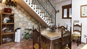 A dining area with a stone wall, a wooden staircase, and a dining table with chairs. - Rural House 'La Acacia' with Private Pool, Wi-Fi and Air Conditioning (Martos)