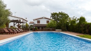 A swimming pool with lounge chairs, a wooden deck, and two white houses with brown roofs. - Rural House 'La Acacia' with Private Pool, Wi-Fi and Air Conditioning (Martos)