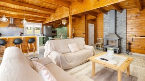 Un interior de madera con sofá, mesa, zona de cocina y chimenea.