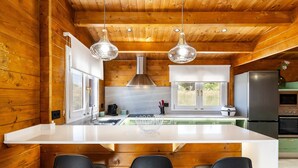 Una cocina moderna con paredes de madera, una isla blanca, taburetes de bar y electrodomésticos de acero inoxidable.