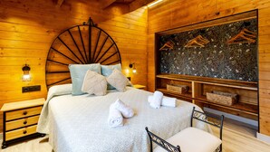 Una habitación de madera con una cama, una lámpara de pared, un adorno en la pared y una pequeña mesa.