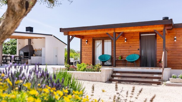 Una cabaña moderna de madera con un porche cubierto, una zona de barbacoa y un área de estar.