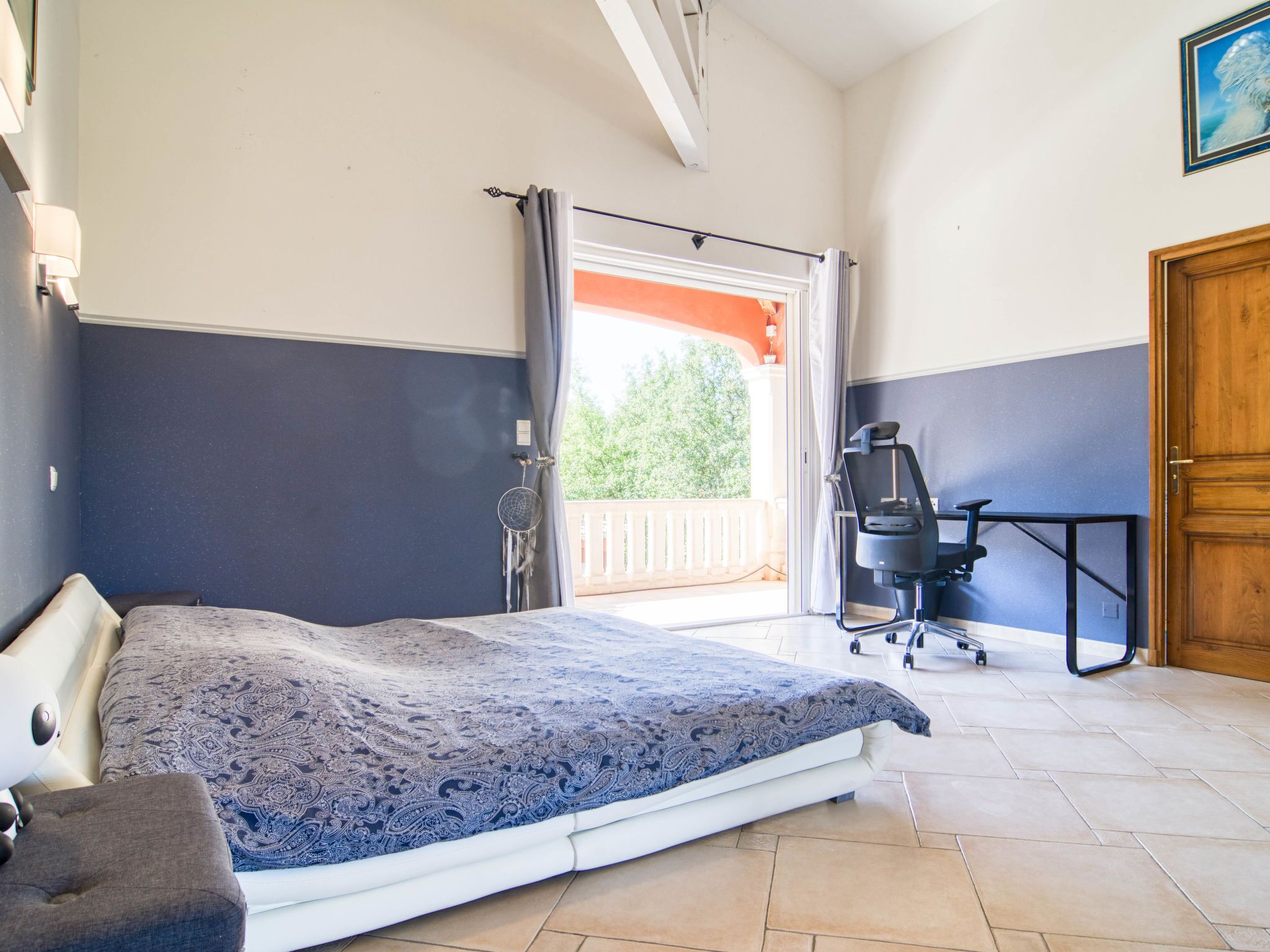 A bedroom with a bed, a desk, and a chair.