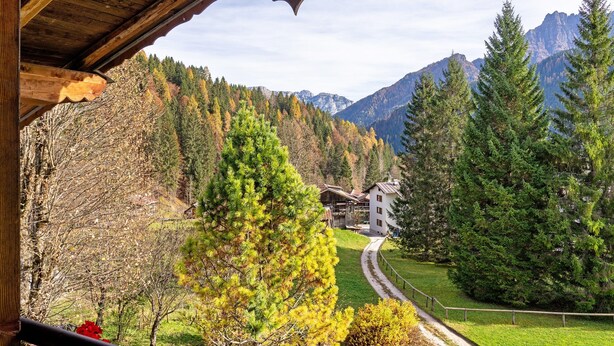 A wooden structure with a view of a mountain landscape, a pathway, and a building in the distance. - Apartment 'Appartamento Palmina' with Mountain View, Shared Garden and Wi-Fi (Falcade)