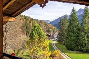 A wooden structure with a view of a mountain landscape, a pathway, and a building in the distance.