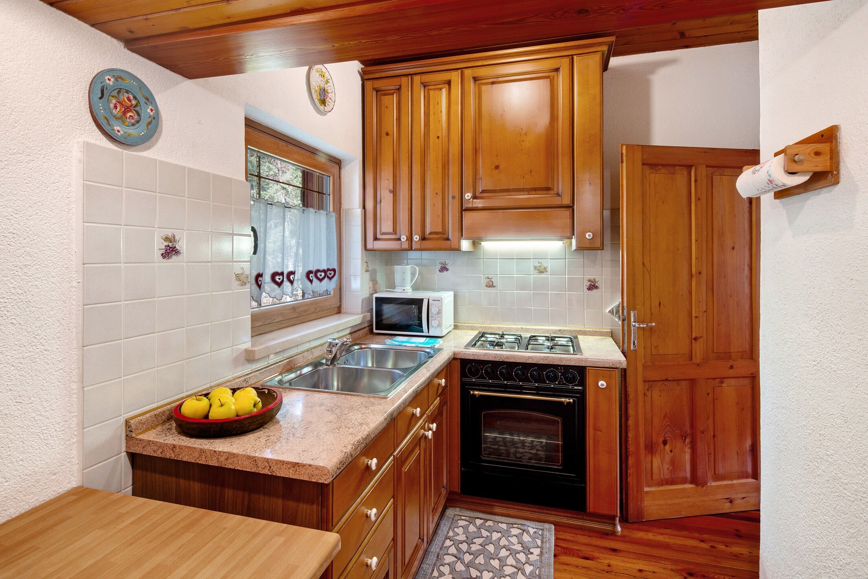 Una cucina con mobili in legno, un forno a microonde, un fornello e un lavello.