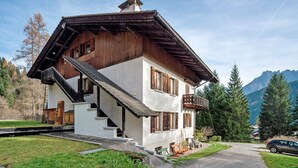 A two-story wooden house with a balcony, a staircase, and a mountain backdrop. - Apartment 'Appartamento Palmina' with Mountain View, Shared Garden and Wi-Fi (Falcade)