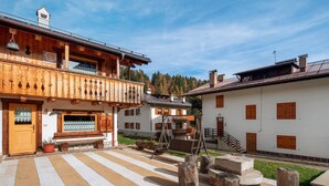 A traditional wooden building with a balcony, a stone pathway, and a wooden swing.