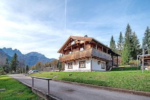 Un chalet de madera con balcón, con montañas al fondo.