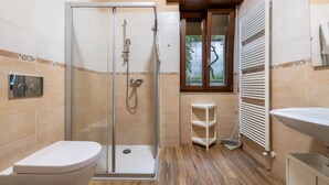 Ein Badezimmer mit Duschkabine, Toilette, Waschbecken und Heizkörper.