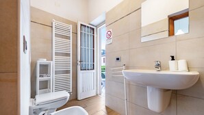 Une salle de bain comprenant des toilettes, un bidet, un lavabo et un miroir.